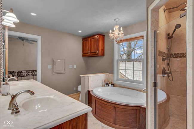 bathroom with a bath, a sink, a shower stall, and ceiling fan with notable chandelier | Image 22