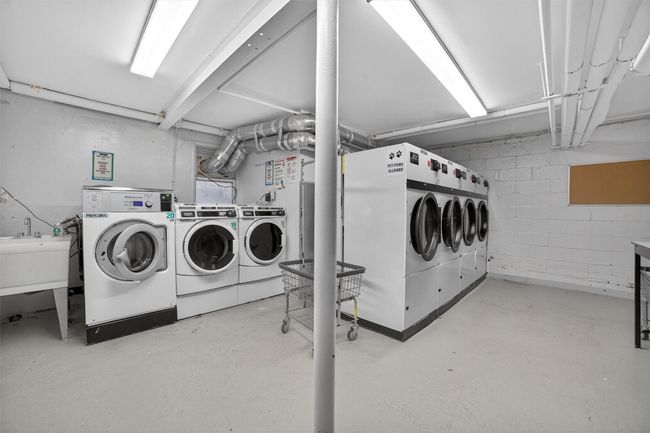 Communal laundry room featuring washing machine and clothes dryer and concrete block wall | Image 19