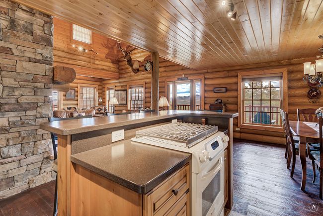 Kitchen featuring white gas range, wooden ceiling, a center island, open floor plan, and dark wood finished floors | Image 15