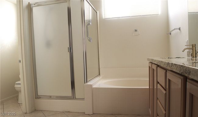 Bathroom with a shower stall, vanity, tile patterned floors, and a bath | Image 30