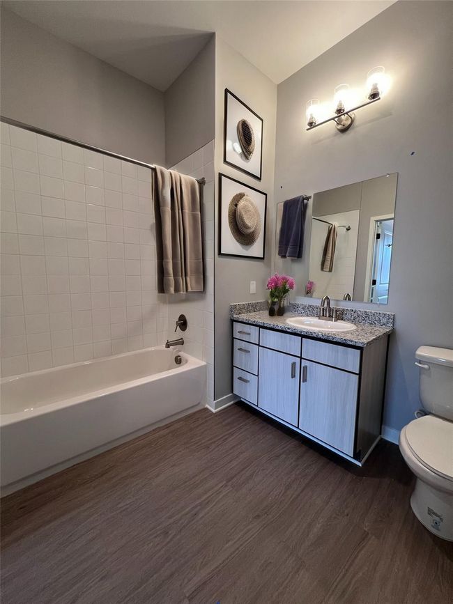 Full bathroom with tiled shower / bath combo, vanity, toilet, and hardwood / wood-style flooring | Image 5