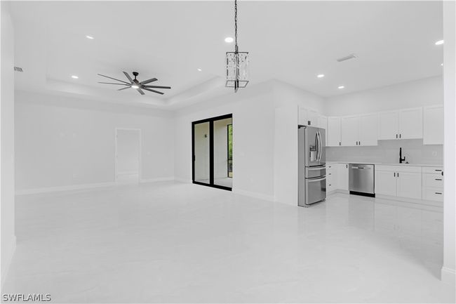 Unfurnished living room featuring ceiling fan, a tray ceiling, sink, and light tile floors | Image 16