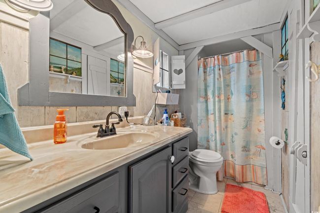 Full bathroom with vanity, tile patterned floors, toilet, shower / bathtub combination with curtain, and tasteful backsplash | Image 18