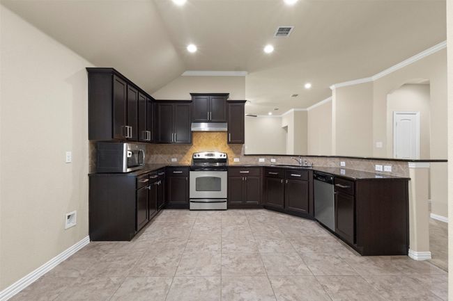 Kitchen featuring appliances with stainless steel finishes, tasteful backsplash, under cabinet range hood, arched walkways, and ornamental molding | Image 9