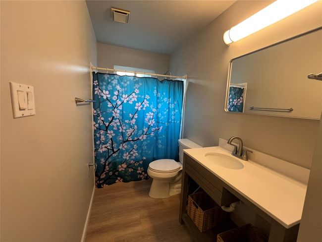 Full bathroom featuring wood finished floors, toilet, vanity, and a shower with shower curtain | Image 17