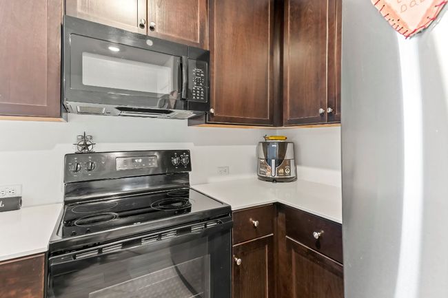 Kitchen featuring black appliances, light countertops, and dark brown cabinetry | Image 19