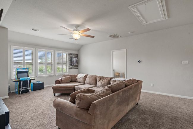 Carpeted living area with attic access, ceiling fan, and baseboards | Image 23