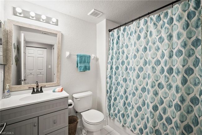 Bathroom featuring a textured ceiling, visible vents, toilet, vanity, and a shower with curtain | Image 11