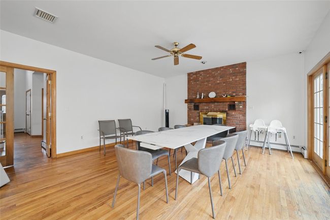Dining space with visible vents, a ceiling fan, light wood-style floors, a brick fireplace, and baseboard heating | Image 7