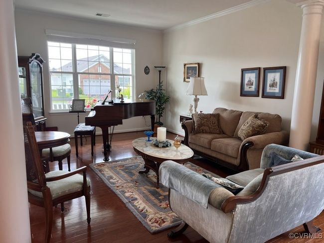 Living room with dark wood-type flooring, crown molding, and ornate columns | Image 8