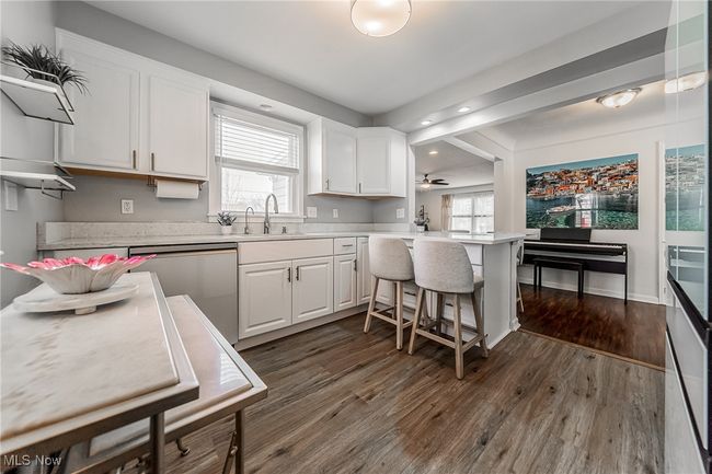 Kitchen featuring white cabinetry, plenty of natural light, dark wood-type flooring, a sink, and dishwasher | Image 15