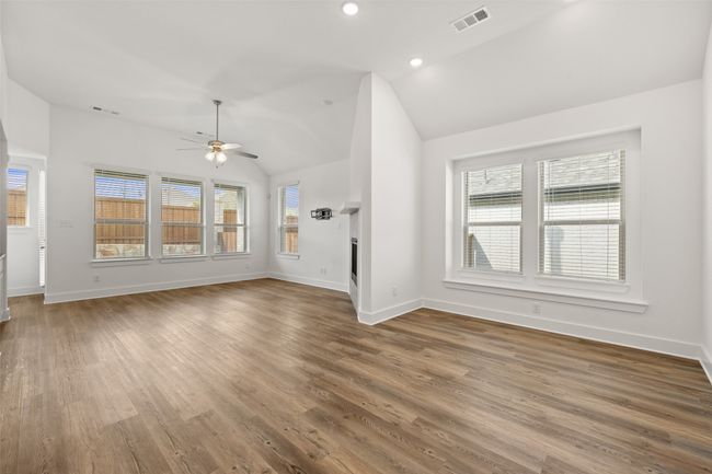Unfurnished living room featuring ceiling fan, visible vents, vaulted ceiling, and wood finished floors | Image 26