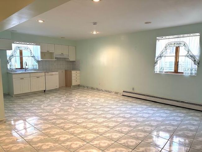 Kitchen featuring tasteful backsplash, sink, a baseboard heating unit, white dishwasher, and white cabinetry | Image 25