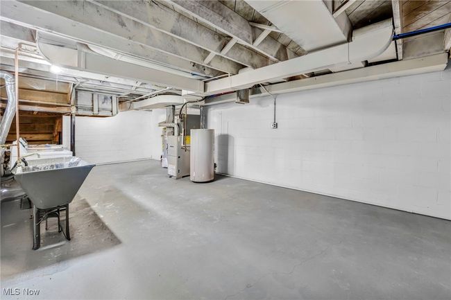 Unfinished below grade area with concrete block wall, gas water heater, and heating unit | Image 24