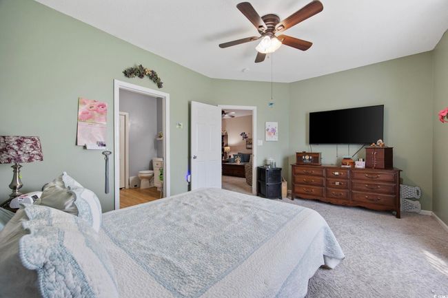 Bedroom featuring light colored carpet, baseboards, a ceiling fan, and connected bathroom | Image 19