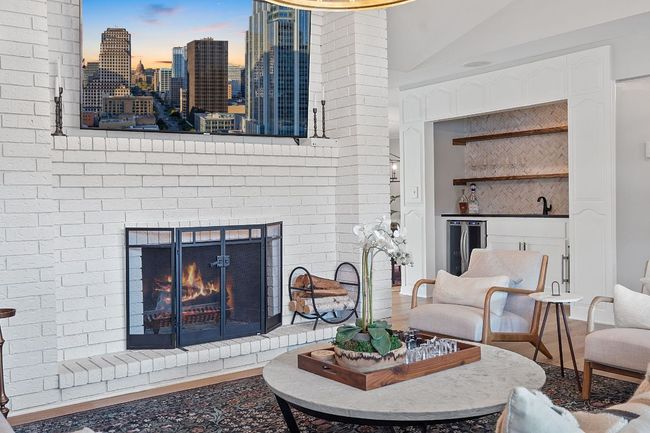 Living area with wood finished floors, custom wet bar, vaulted ceiling, and a brick fireplace | Image 4
