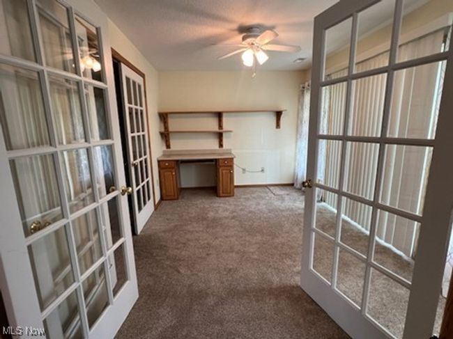 Unfurnished office with french doors, dark carpet, and ceiling fan | Image 10