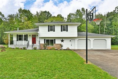 Split level home with covered porch, a garage, and a front yard | Image 1