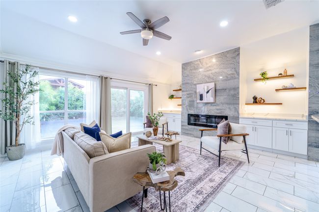 Living area featuring light marble finish flooring, a premium fireplace, ceiling fan, and recessed lighting | Image 14