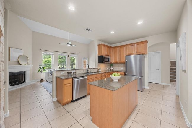 Kitchen featuring appliances with stainless steel finishes, a peninsula, decorative backsplash, and granite counters | Image 9