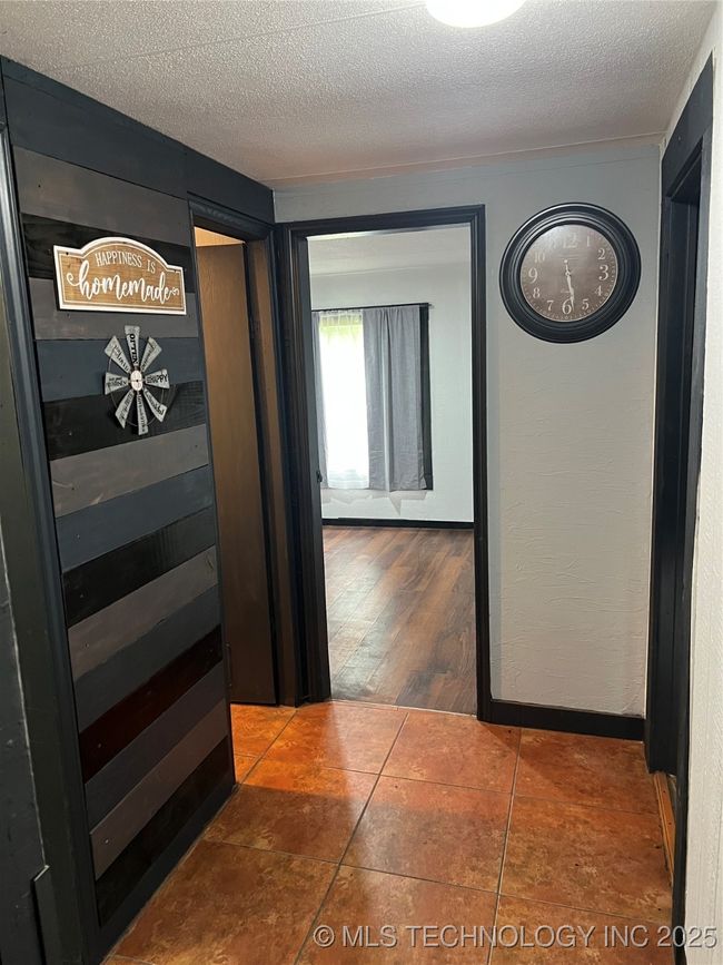 Hallway featuring a textured ceiling and tile patterned floors | Image 19