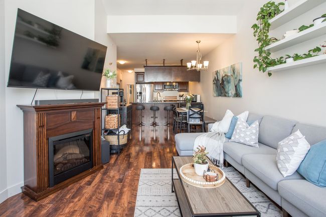 Living room with dark wood finished floors, a notable chandelier, and a glass covered fireplace | Image 13