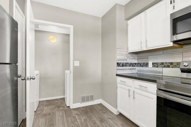 Kitchen featuring backsplash, visible vents, appliances with stainless steel finishes, and white cabinets | Image 12