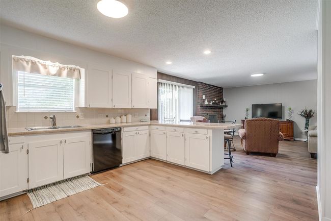 Kitchen featuring dishwasher, a textured ceiling, a peninsula, a fireplace, and light countertops | Image 17