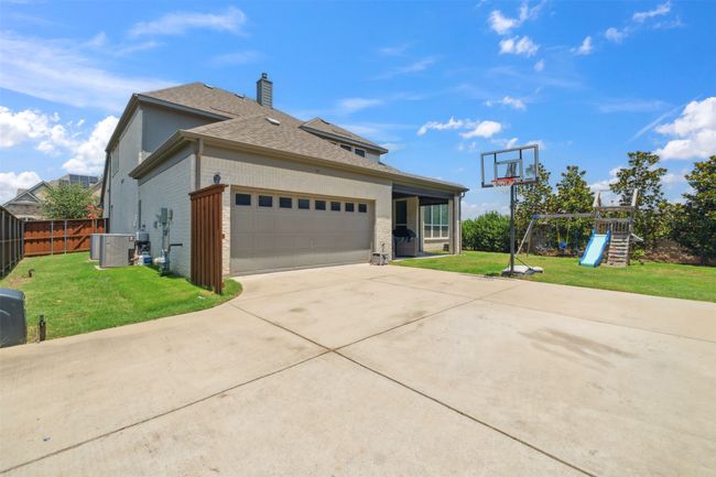 View of home's exterior featuring brick siding, a shingled roof, concrete driveway, an attached garage, and a playground | Image 35