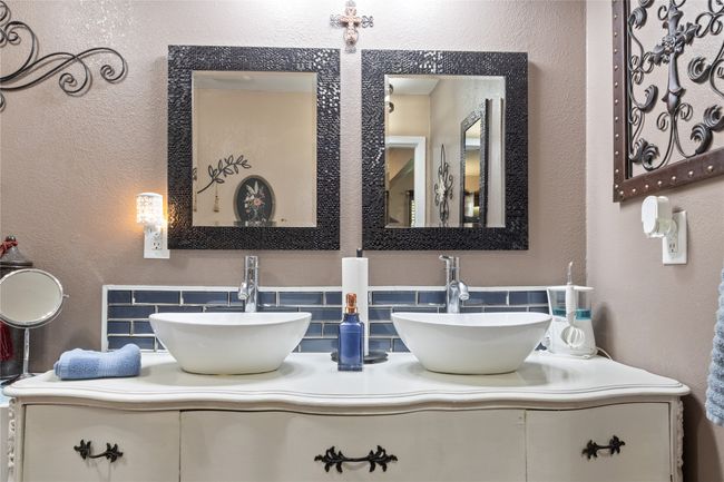 Bathroom featuring decorative backsplash, double vanity, and a textured wall | Image 12