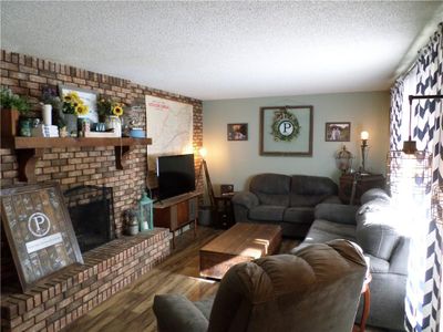 Living room with hardwood / wood-style floors, a fireplace, and a textured ceiling | Image 2