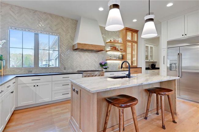 Kitchen with built in refrigerator, custom exhaust hood, a sink, and light wood-style flooring | Image 19