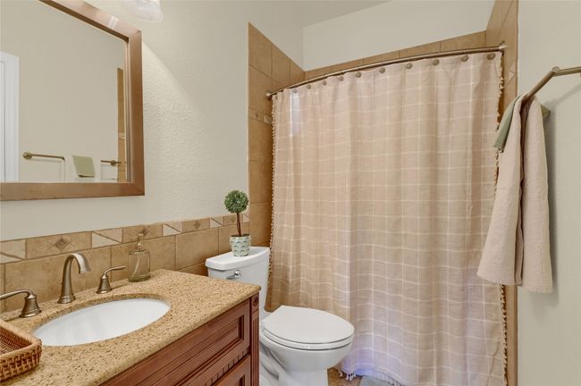 Bathroom with tile walls, toilet, vanity, curtained shower, and wainscoting | Image 20