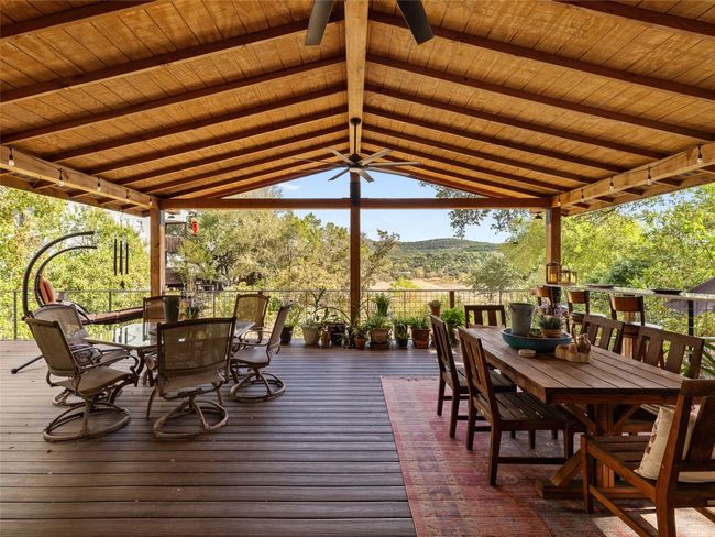 Covered area of the back patio has ceiling fans and a raised bar/dining area. | Image 9