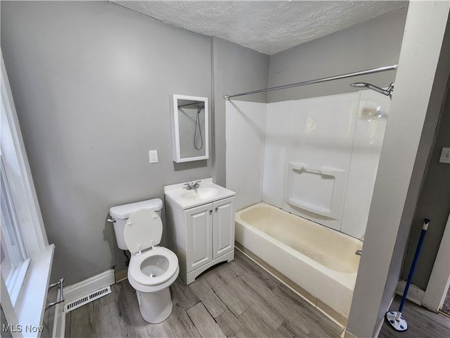 Full bathroom featuring a textured ceiling, wood-type flooring, toilet, vanity, and bathing tub / shower combination | Image 14