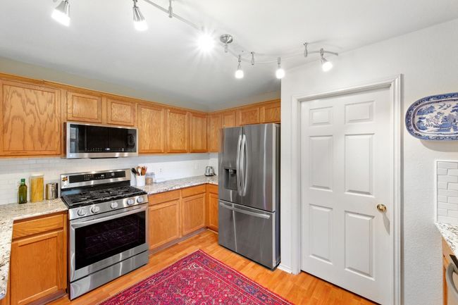 Kitchen with appliances with stainless steel finishes, light wood-style floors, light stone countertops, and decorative backsplash | Image 12