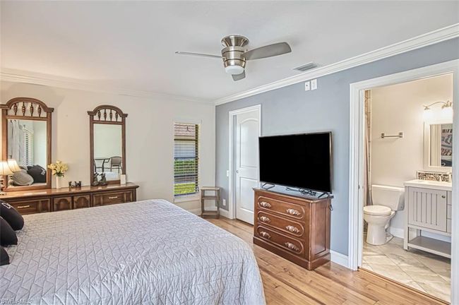 Bedroom with baseboards, visible vents, ornamental molding, and light wood finished floors | Image 35