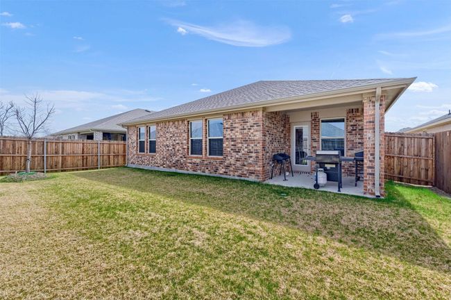 Rear view of house with brick siding, a patio, a fenced backyard, and roof with shingles | Image 29