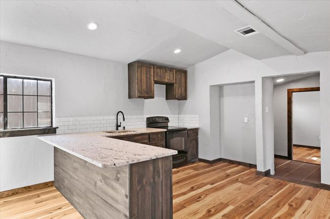 Kitchen with a sink, electric range, visible vents, and light wood-style flooring | Image 17