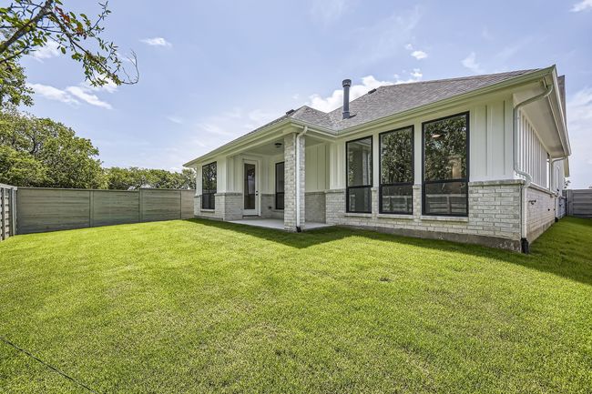 Rear view of property featuring board and batten siding, brick siding, and roof with shingles | Image 29