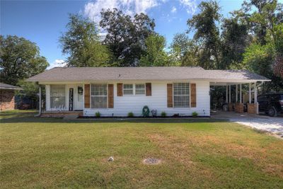 Ranch-style house featuring a front lawn, a carport, and covered porch | Image 1