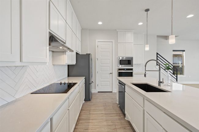 Kitchen featuring light wood-style floors, white cabinets, decorative backsplash, light countertops, and recessed lighting | Image 14
