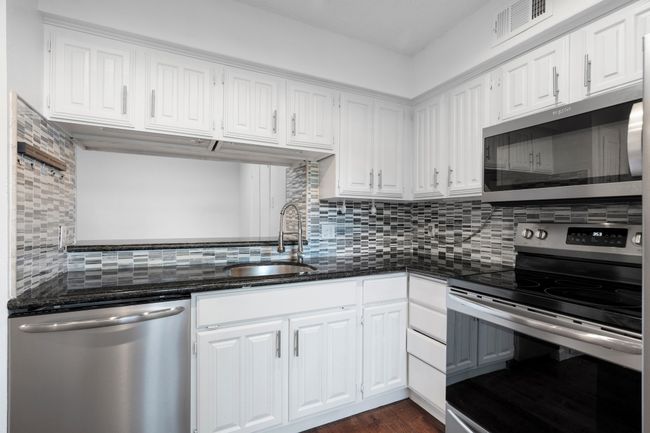 Kitchen with visible vents, a sink, white cabinetry, stainless steel appliances, and backsplash | Image 13