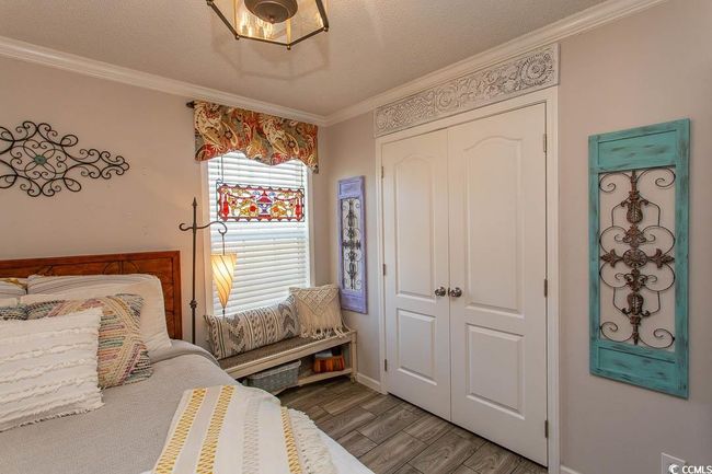 Bedroom with a textured ceiling, crown molding, baseboards, a closet, and wood finished floors | Image 24