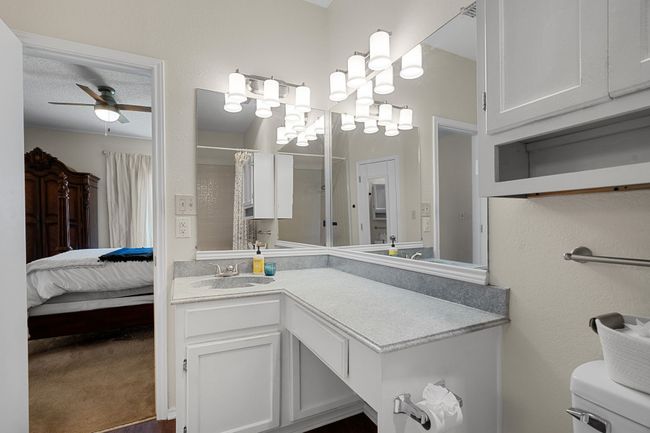 Ensuite bathroom featuring a ceiling fan, vanity, and curtained shower | Image 16