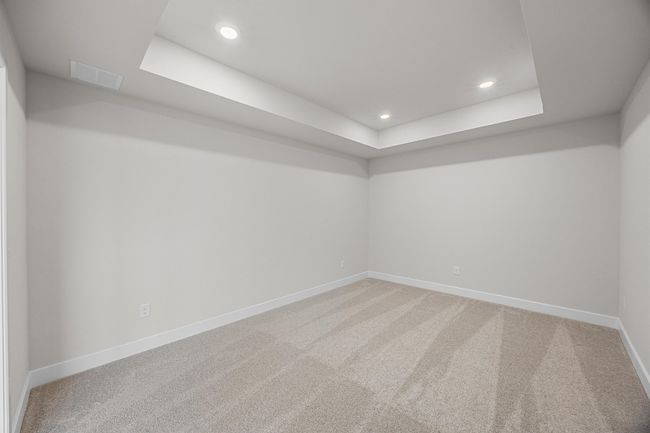 Carpeted empty room featuring a raised ceiling, baseboards, and recessed lighting | Image 24