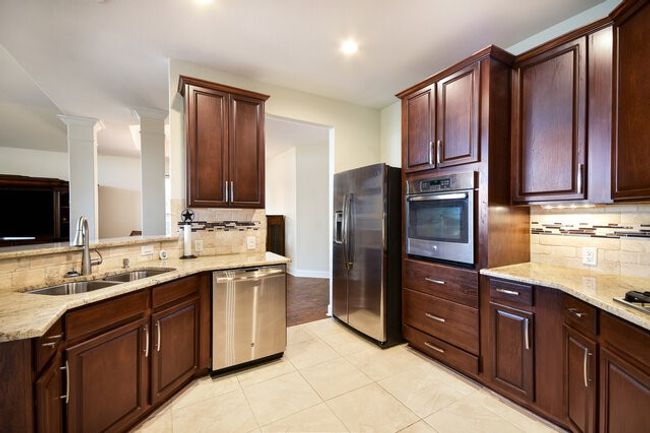 Kitchen with appliances with stainless steel finishes, a sink, backsplash, light stone countertops, and recessed lighting | Image 10