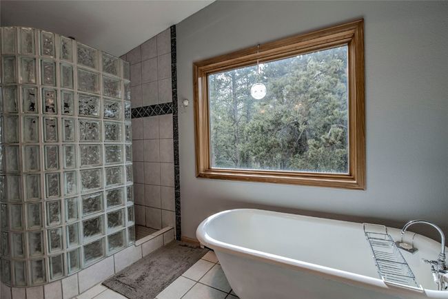 Bathroom with a freestanding tub, walk in shower, and tile patterned flooring | Image 32