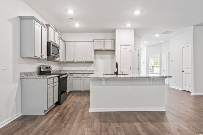 Kitchen with appliances with stainless steel finishes, gray cabinets, light stone countertops, dark wood-style flooring, and recessed lighting | Image 38