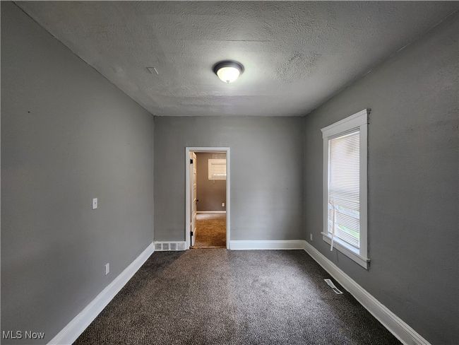 Unfurnished bedroom featuring a textured ceiling and dark colored carpet | Image 7